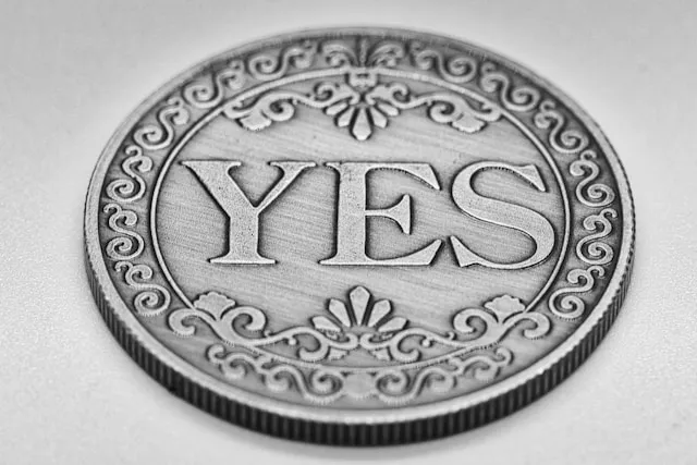 A close-up shot of a silver coin suspended mid-air during a coin flip, photographed by Gidlark on Unsplash